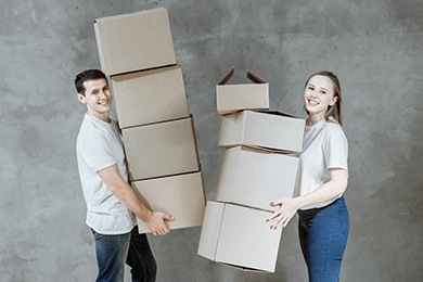 Happy young married couple man and woman with boxes for moving in new home